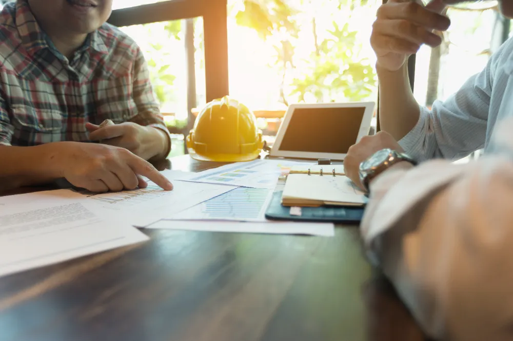 Architects reviewing blueprints with hard hats and tools on the table, representing Restorations Unlimited’s detailed build planning process focused on clarity, scheduling, and precision