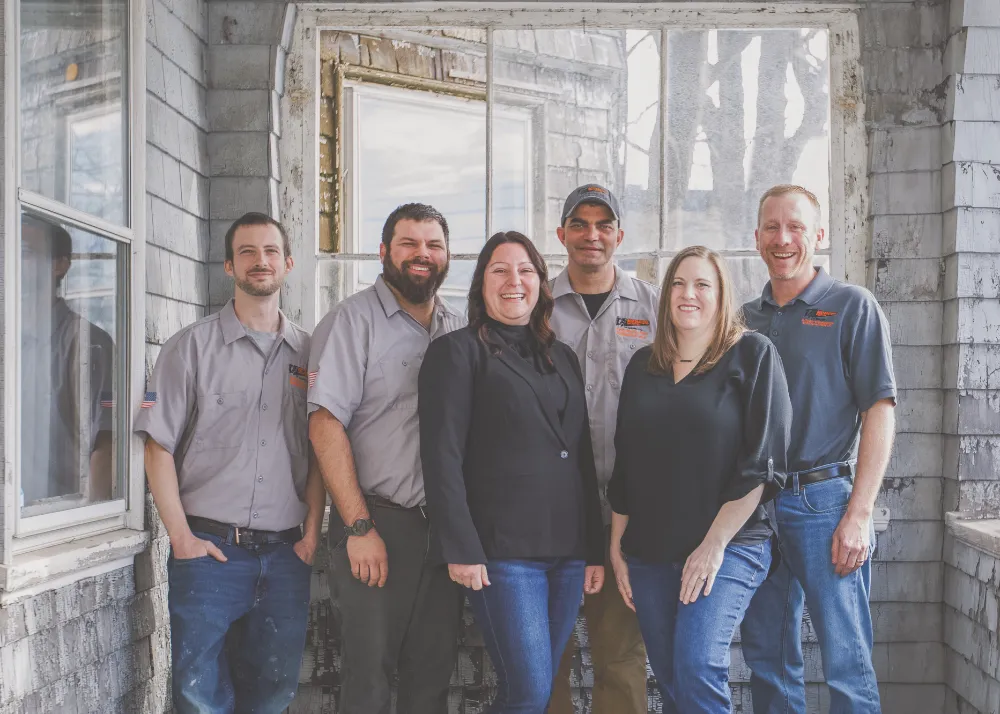 Restorations Unlimited team standing together outside a home, showcasing their friendly professionalism and commitment to quality craftsmanship for clients in Maine