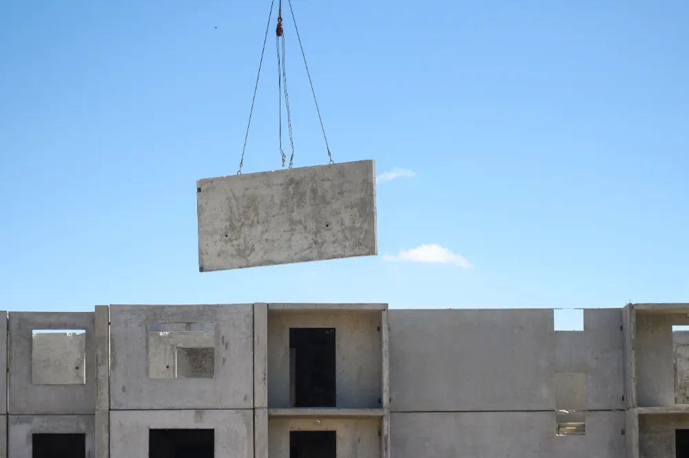 Crane lifting a concrete panel into place on a commercial building under renovation, symbolizing Restorations Unlimited’s ability to transform outdated spaces into modern, functional business assets.