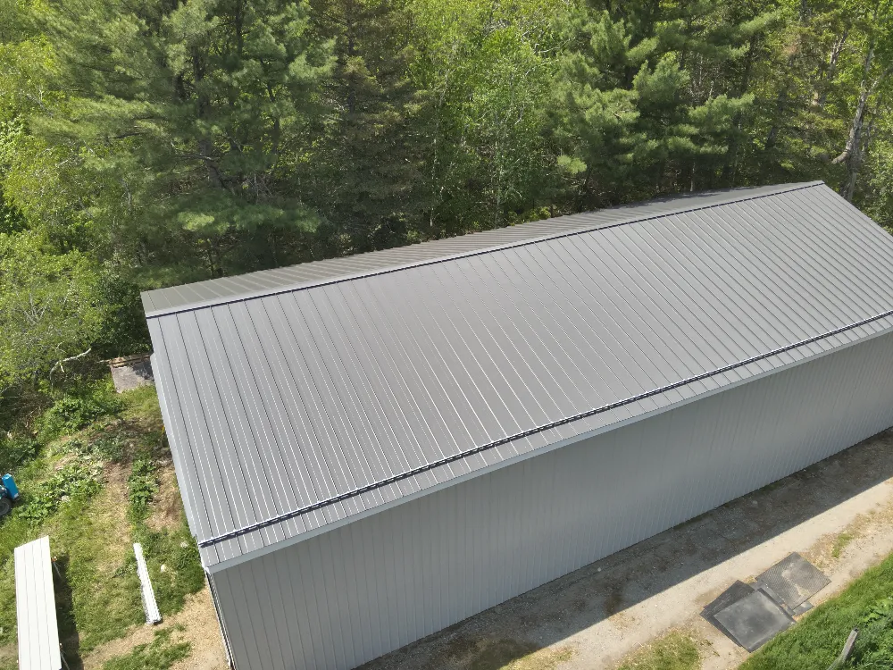 Newly installed metal commercial roof surrounded by trees, representing Restorations Unlimited’s durable, weather-resistant roofing solutions designed for performance and longevity in Maine’s toughest conditions.