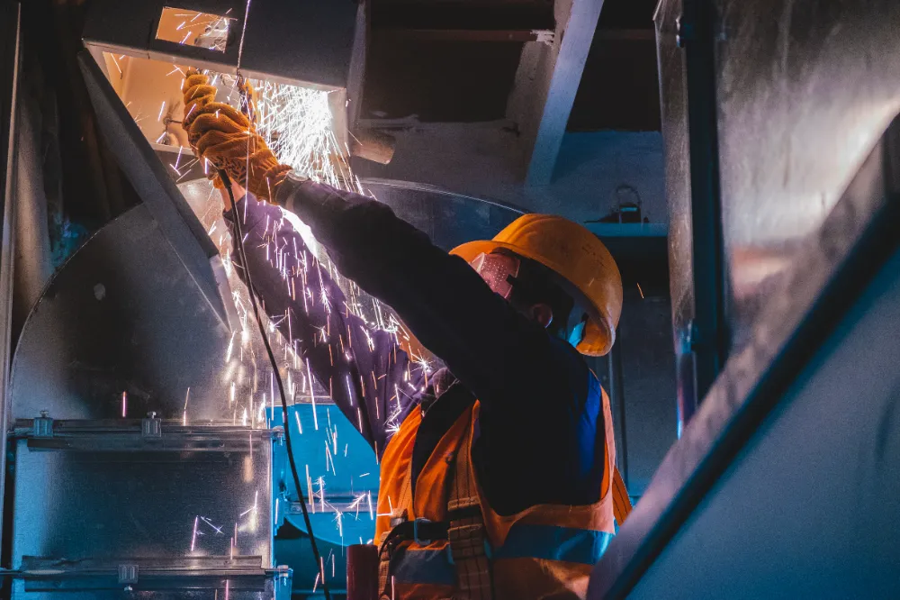 Construction worker using a grinder with sparks flying inside a commercial facility, representing Restorations Unlimited’s reliable repair and preventative maintenance services that keep Maine businesses running smoothly.