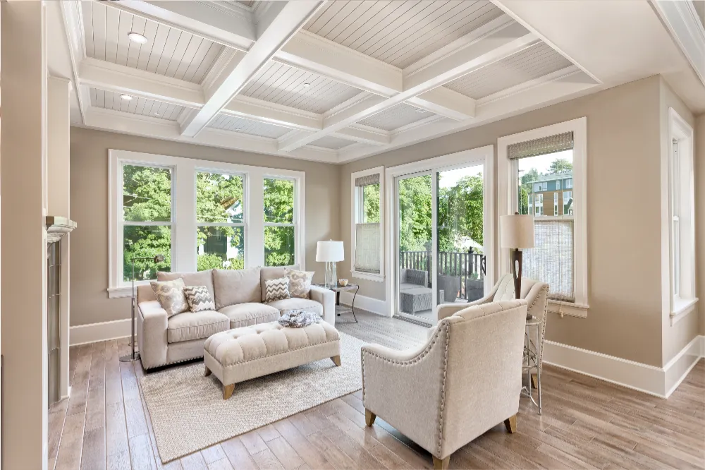 Bright and elegant living room with large windows and coffered ceiling—showcasing Restorations Unlimited’s seamless residential home additions that expand space and enhance natural light in Maine homes.