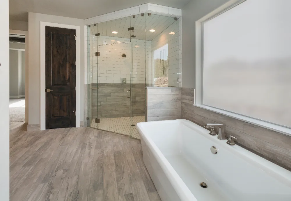 Elegant bathroom featuring a freestanding tub, walk-in glass shower, and wood accents—showcasing Restorations Unlimited’s focus on precision craftsmanship and long-lasting, functional bathroom design in Maine.