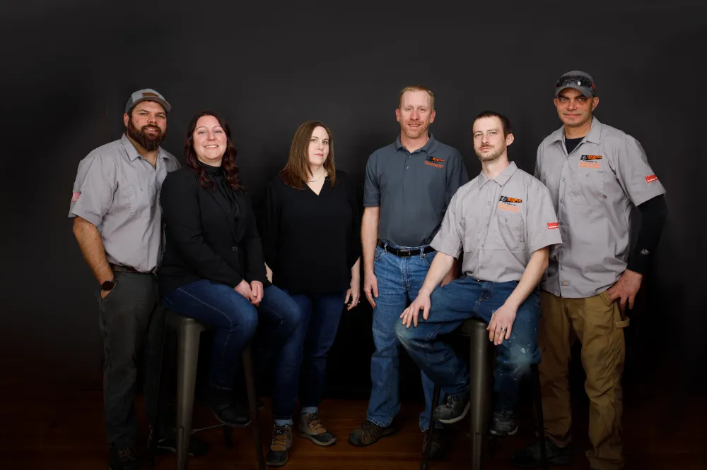 The Restorations Unlimited team posing together in a studio setting, representing the unified crew that manages projects and client communication through JobTread, as featured on the About page.