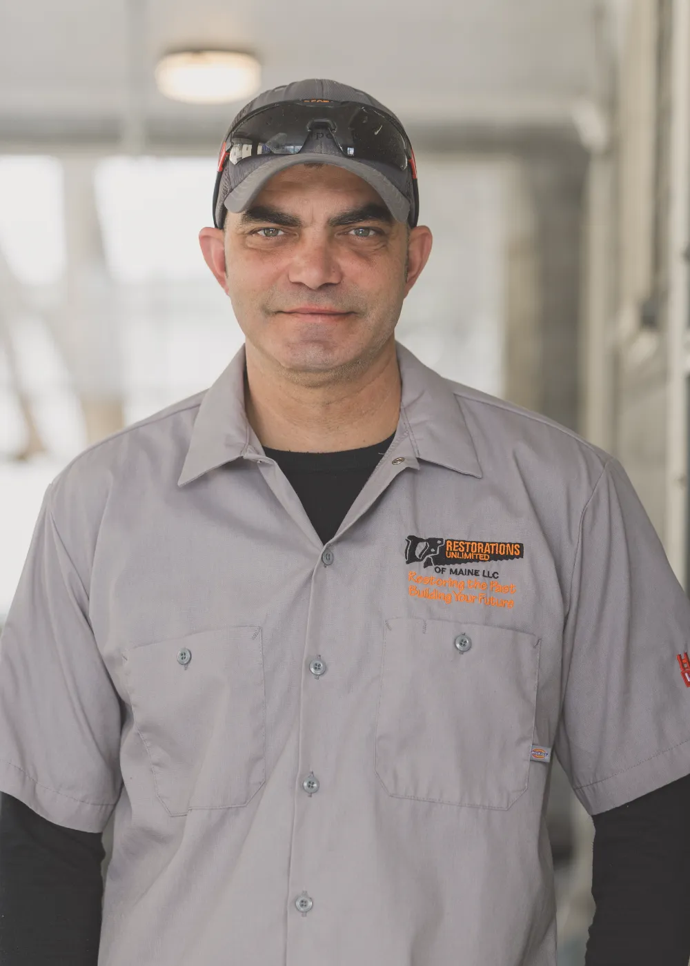 Joe Infante of Restorations Unlimited wearing a gray work shirt and hat, representing his 26 years of construction experience, hands-on expertise, and no-nonsense work ethic.
