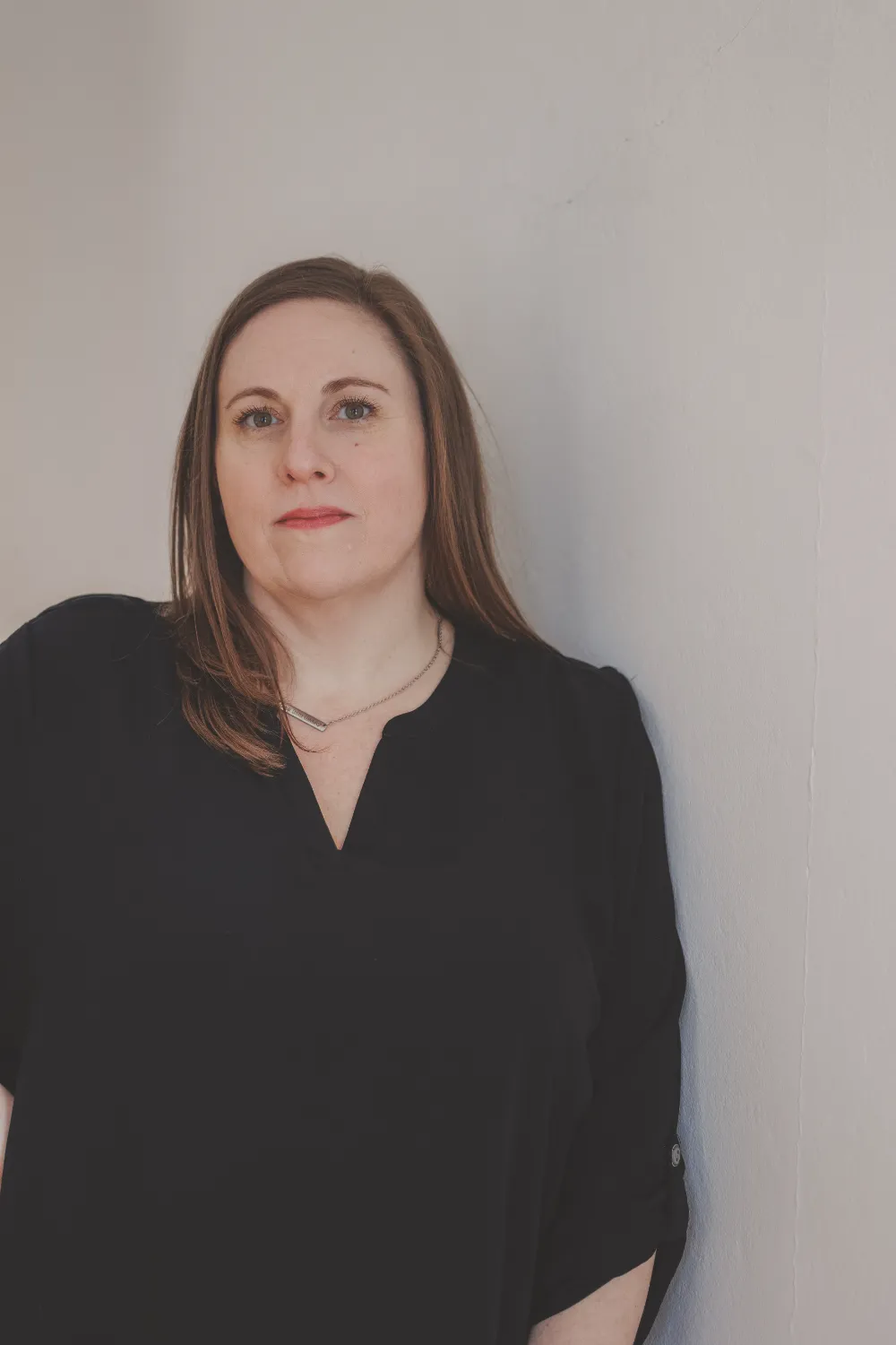 Carrie Schwabenbauer of Restorations Unlimited standing against a light-colored wall, representing her role in project coordination, communication, and keeping builds on track from start to finish.