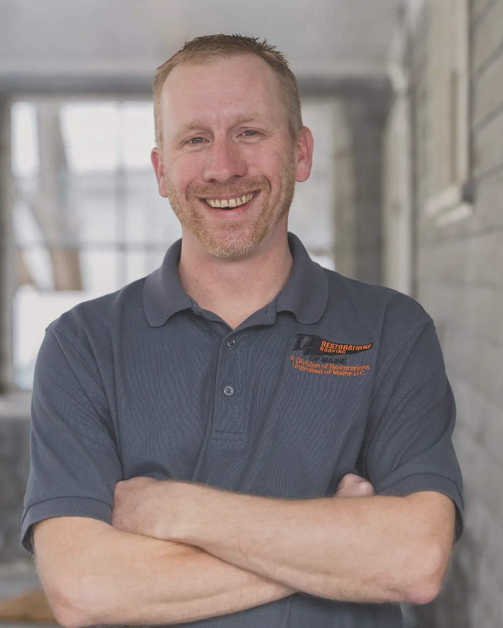 Scott Walton of Restorations Unlimited smiling with arms crossed in a company polo, representing his honest, hands-on approach and dedication to helping homeowners bring their renovation ideas to life.