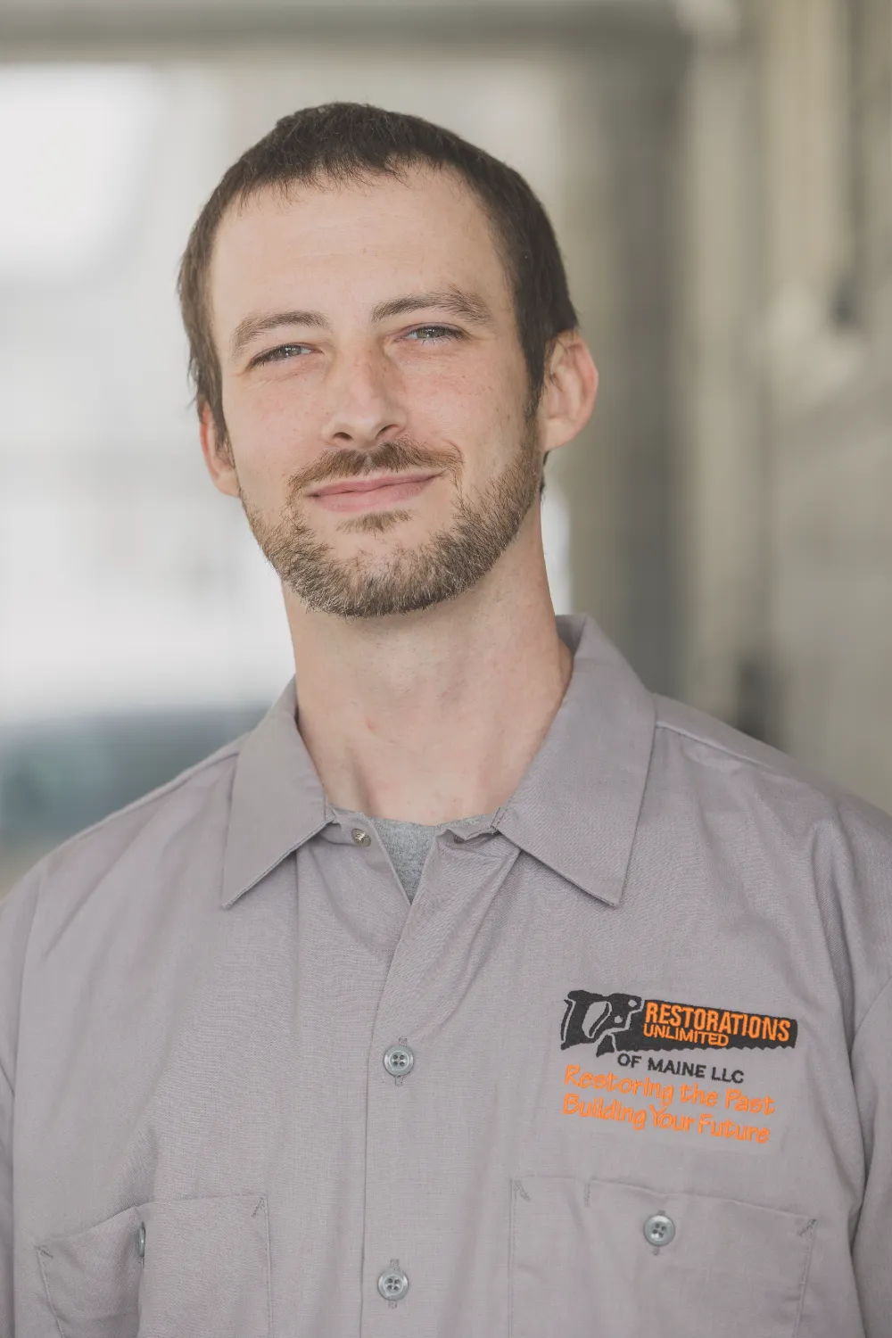 Jeremy Curtis of Restorations Unlimited wearing a company work shirt, representing his craftsmanship, reliability, and dedication to building lasting results for both clients and his Maine community.
