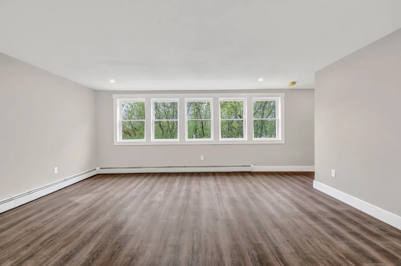 Newly renovated living room with wood flooring and large windows in Brewer, Maine, representing Restorations Unlimited’s home renovation services