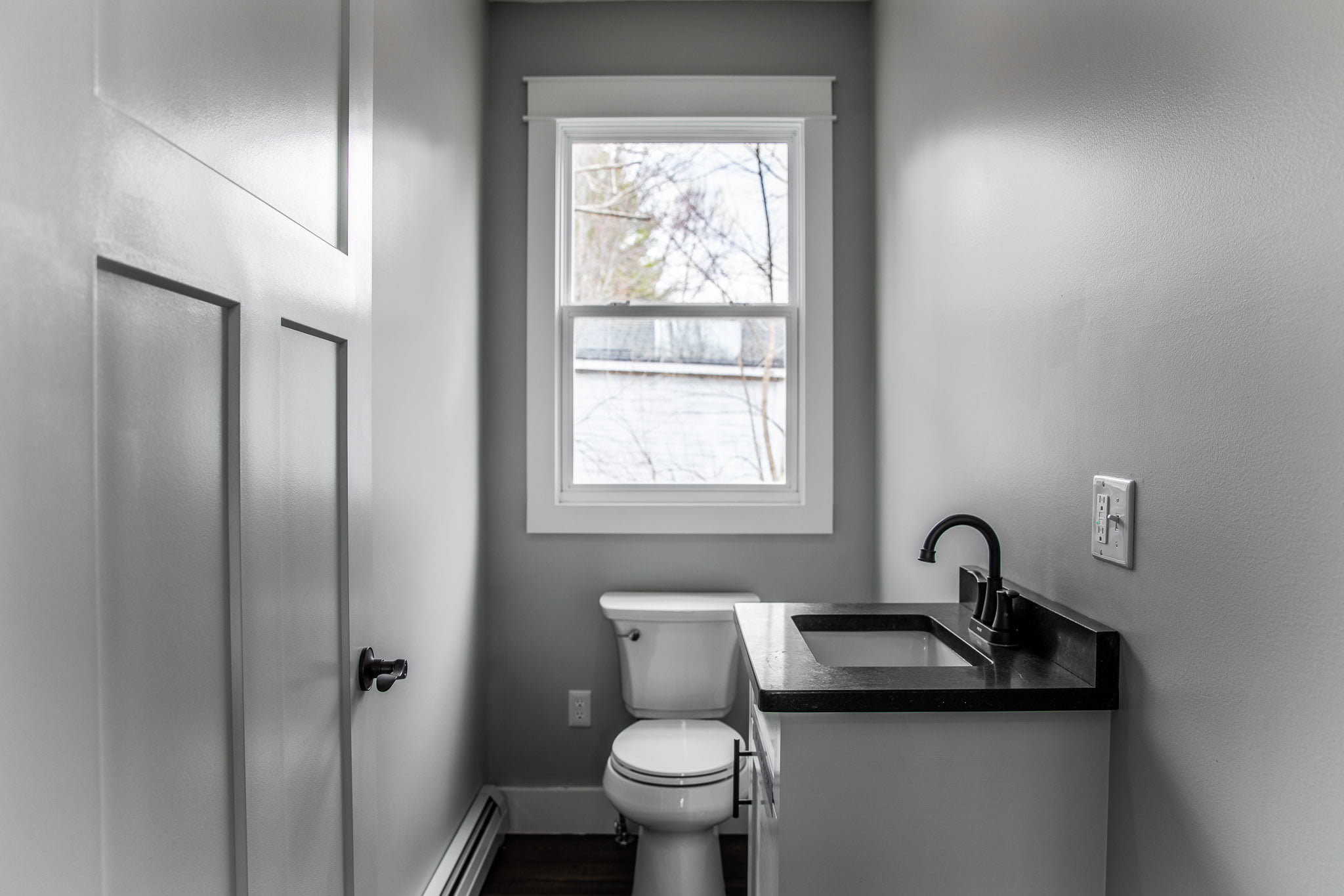 Modern bathroom with white walls and black countertop in Veazie, Maine, representing Restorations Unlimited’s bathroom remodeling services