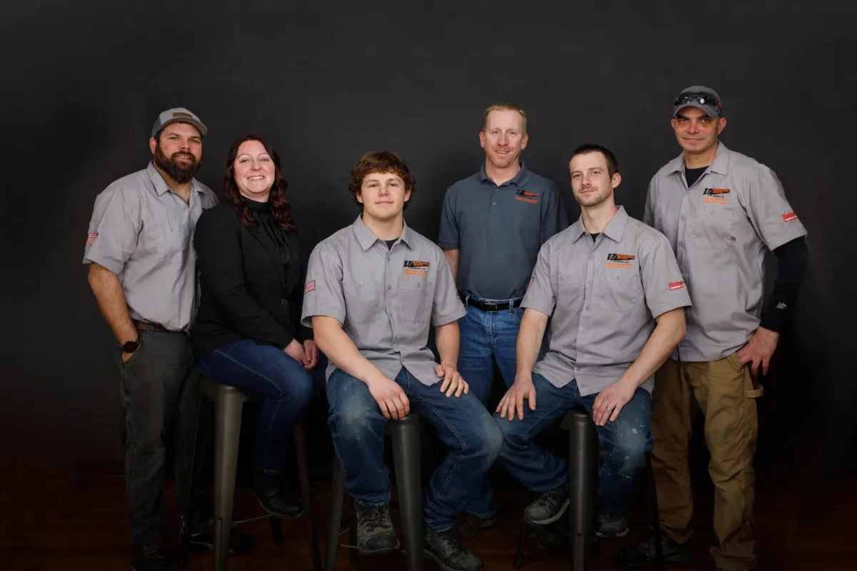 The Restorations Unlimited team posing together in a studio setting, representing the unified crew that manages projects and client communication through JobTread, as featured on the About page.