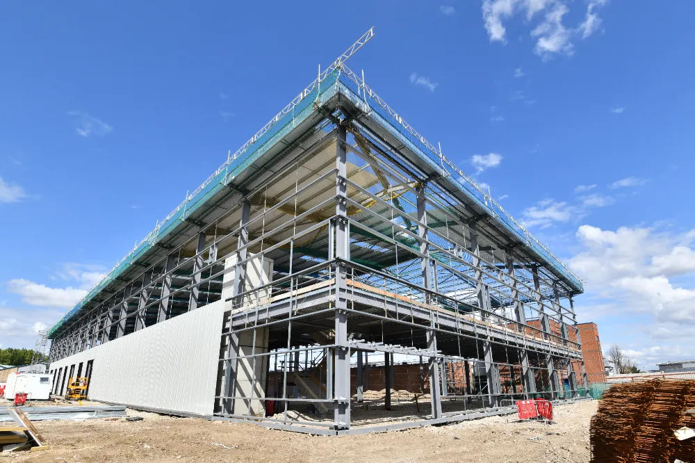 Steel-framed commercial building under construction with scaffolding and siding installation in progress, representing Restorations Unlimited’s expertise in developing purposeful, code-compliant commercial spaces across Maine.