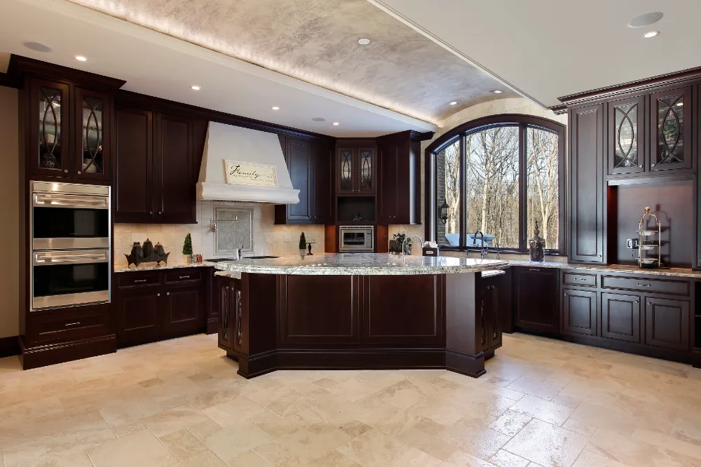 Luxury kitchen renovation featuring rich dark wood cabinetry, a large center island, and elegant lighting—representing Restorations Unlimited’s whole home renovation services in Maine that improve function, flow, and timeless design.