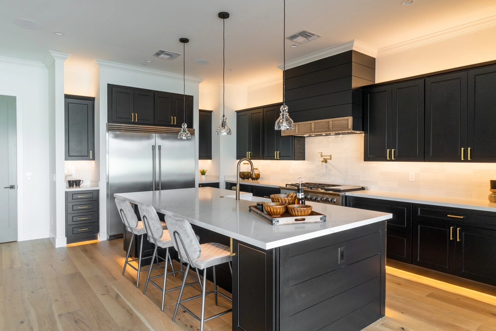 Modern kitchen remodel featuring black cabinetry, pendant lighting, and a large center island—highlighting Restorations Unlimited’s custom kitchen remodeling services in Maine for beauty, function, and lasting quality.