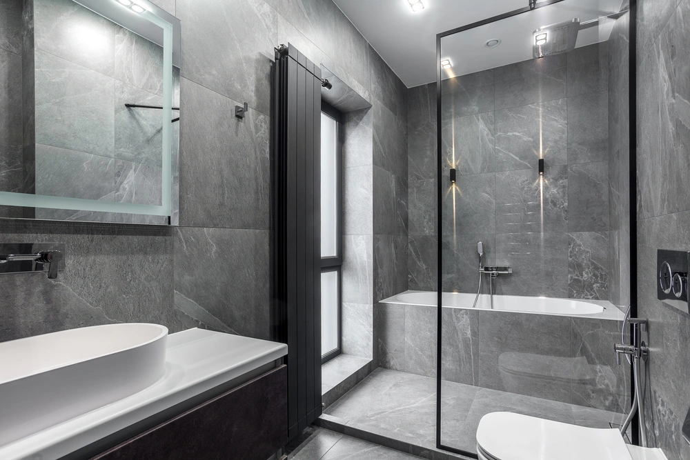 Modern gray tile bathroom with frameless glass shower, floating vanity, and sleek lighting—showcasing Restorations Unlimited’s bathroom remodeling services in Maine focused on function, comfort, and timeless design.
