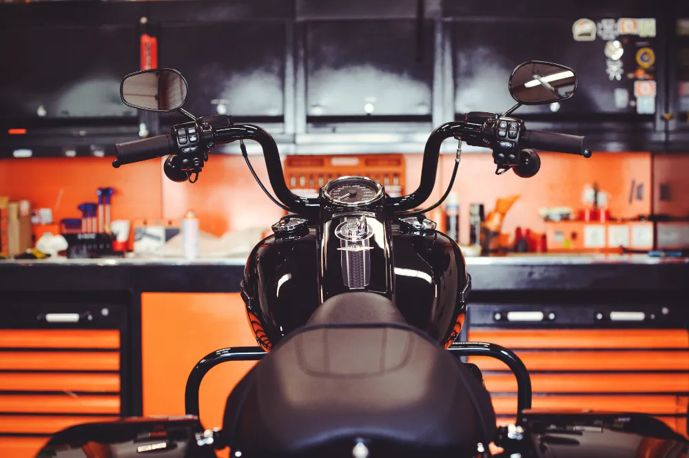 Custom garage interior with a motorcycle parked in front of sleek black and orange cabinetry—showcasing Restorations Unlimited’s garage construction services in Maine focused on storage, security, and style.