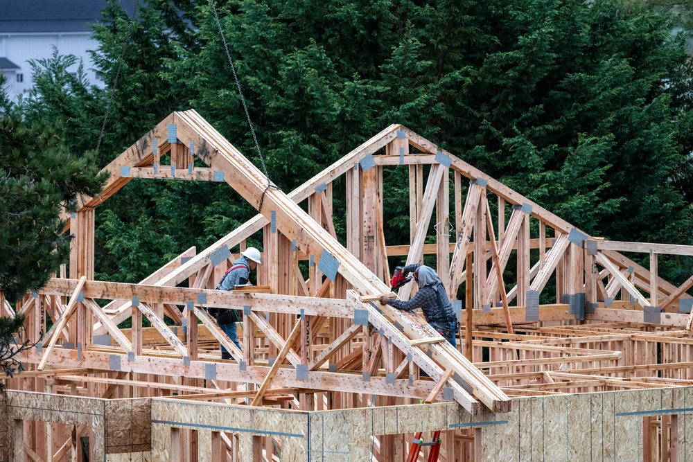 Home roofing construction in progress with workers installing wooden trusses—representing Restorations Unlimited’s roofing services in Maine built for durability, longevity, and protection against harsh weather.