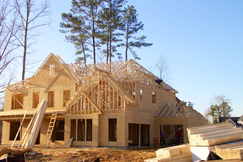 Wood-framed house under construction surrounded by trees—showcasing Restorations Unlimited’s start-to-finish new construction services for residential and light commercial projects across Maine.