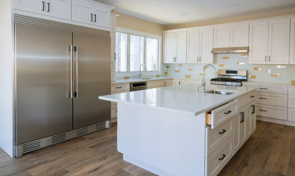 Modern kitchen renovation featuring white cabinetry, stainless steel appliances, and a spacious island—capturing Restorations Unlimited’s design-build approach to functional, lasting kitchen remodels in Maine.