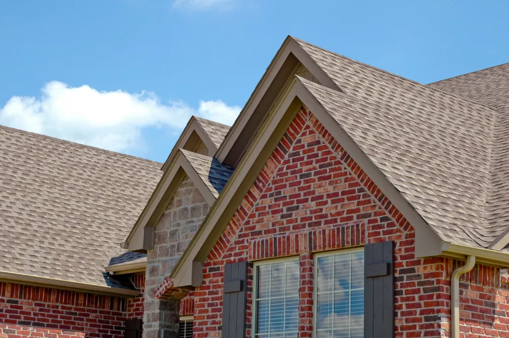 Close-up of a new shingle roof on a red brick home with clean lines and precise detailing—showcasing Restorations Unlimited’s professional roofing craftsmanship and planning excellence in Maine.