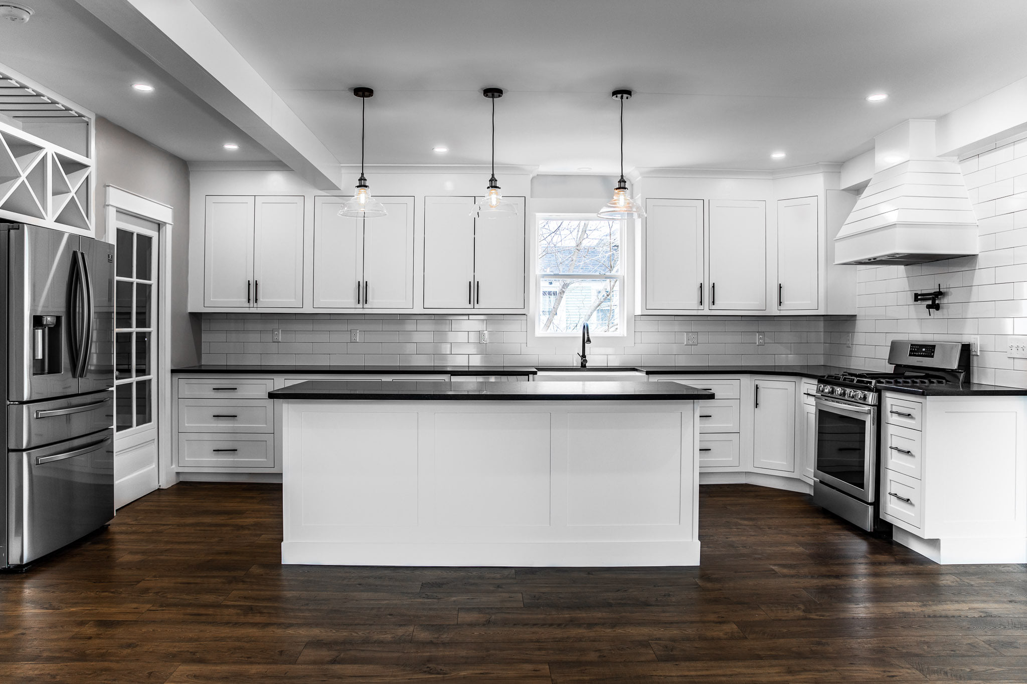Modern white kitchen with island, pendant lighting, and hardwood floors, representing Restorations Unlimited’s professional design process and commitment to quality craftsmanship